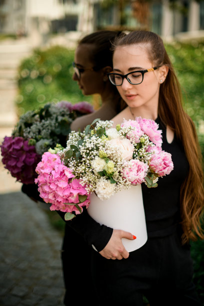 混合花卉组成与绣球花，牡丹康乃馨，吉思兰在帽盒在妇女的手图片下载