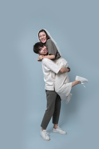 亚洲年轻夫妇穿休闲装，新娘戴面纱。幸福和享受照片一起在工作室浅蓝色背景。图片下载