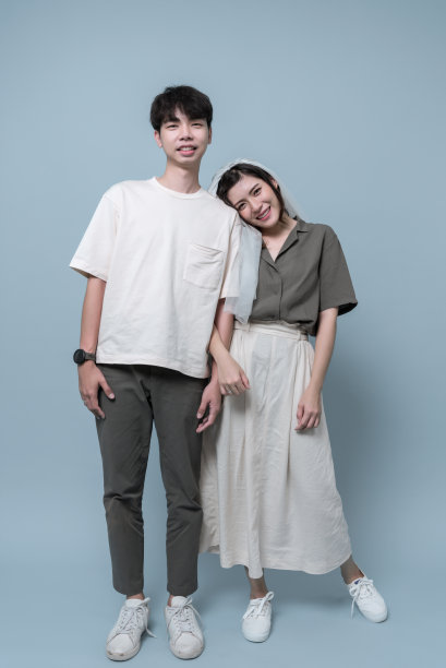 亚洲年轻夫妇穿休闲装，新娘戴面纱。幸福和享受照片一起在工作室浅蓝色背景。图片下载