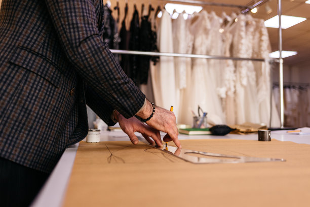 年轻的严肃的留着胡子的裁缝看着画在木桌附近的线在惊人的工作室与古董家具和人体模型图片下载