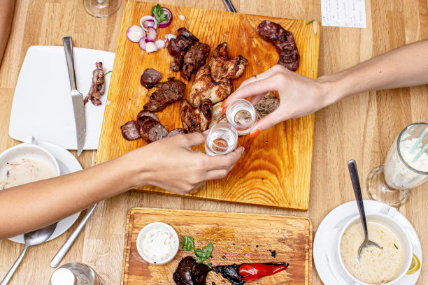 人们在餐桌上喝着杜松子酒和俄罗斯伏特加，还有羊肉串和美味的开胃菜，照片俯视图图片下载