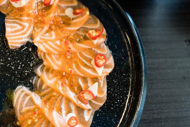 将生鲑鱼切成薄片，倒入泰式辣酱，用辣椒和大蒜装饰图片下载