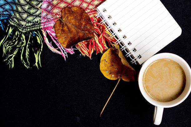 秋天呆在家里的舒适。上面的照片是一杯热咖啡，一张拼凑的毯子，枫叶，在黑色的孤立背景上，有复制空间图片下载