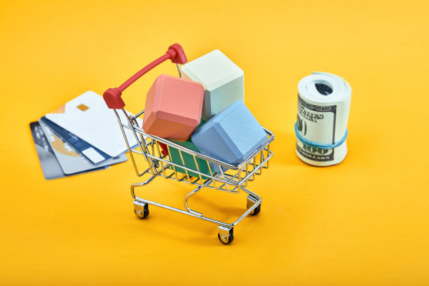 迷你购物手推车装满了彩色砖块，黄色背景的美元钞票和信用卡。电车和钱。金融危机或购物狂概念。平铺，复制空间图片下载