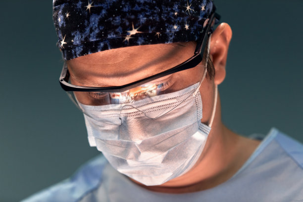 医生在黑暗的手术室里做手术，背景是一盏灯，一位专业的外科医生在紧张的手术中。图片下载