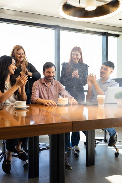 一个人吹着同事给他的生日蛋糕上的蜡烛图片下载