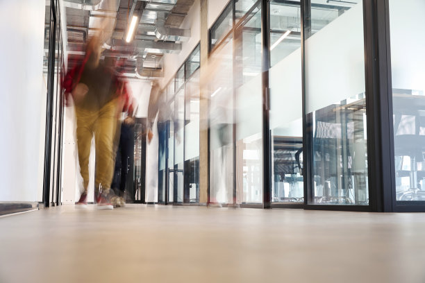 模糊的视线，人们沿着办公楼明亮的大厅走着图片下载