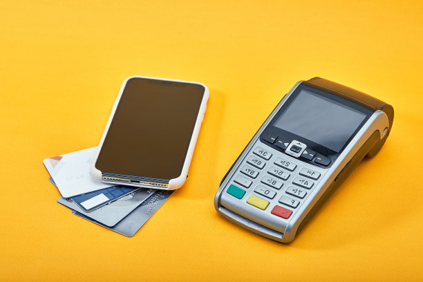 无线支付终端，用于信用卡或NFC支付，黄色背景为手机和信用卡。广告、全景的复制空间图片下载