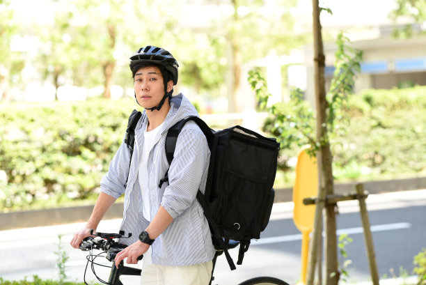 年轻的亚洲男子背着背包，骑着自行车提供送货服务图片下载