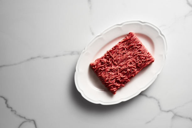 生的和新鲜的碎牛肉在白色盘子，白色大理石背景。简约的美食照片，高调。俯视图，复制空间图片下载