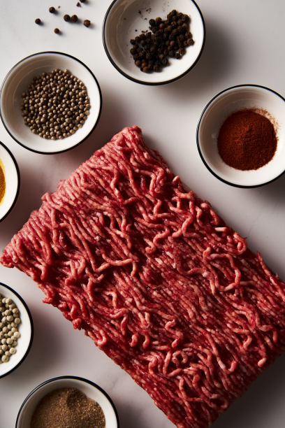 生的和新鲜的碎牛肉在白色大理石背景与香料烹饪。简约的美食照片，高调。图片下载