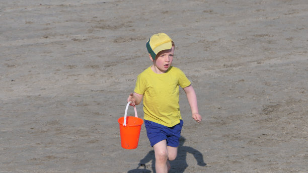 在英国的海滩上，孩子在玩水桶和铲子，同时保持社交距离图片下载