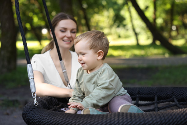 快乐的保姆和可爱的小男孩在户外荡秋千图片下载