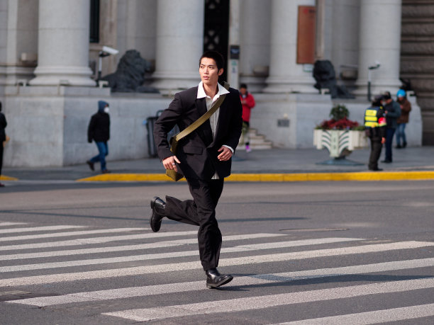 英俊的中国年轻人的肖像，黑色短发，穿着黑色运动夹克，在阳光明媚的冬日穿过现代城市建筑背景的街道，男性时尚，酷的亚洲年轻人。图片下载