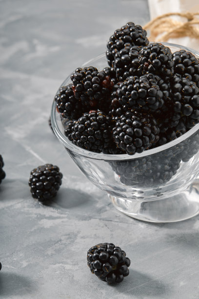 一个装满黑莓的小玻璃杯。特写，成熟的黑莓浆果在灰色背景交付的产品，复制空间，照片的商店目录。图片下载