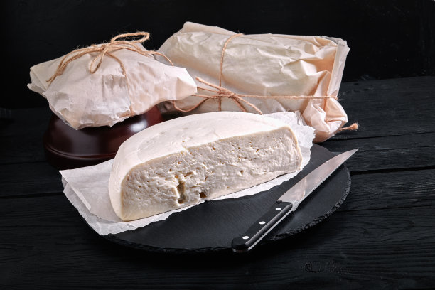 Suluguni格鲁吉亚奶酪切片在木板上的深色背景，特写，环保包装。杂货店照片图片下载