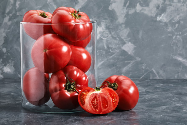 灰色背景玻璃花瓶里的大红番茄特写，番茄概念，复制空间。杂货店照片图片下载