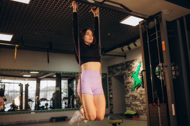 可爱的年轻肌肉女孩在健身房做引体向上运动。图片下载