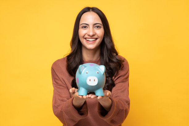 可爱的人的照片，手握钱银行猪隔离在黄色背景股票照片图片下载