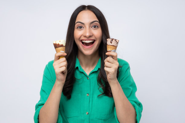 有吸引力的年轻女子吃冰淇淋，站在白色背景的股票照片图片下载