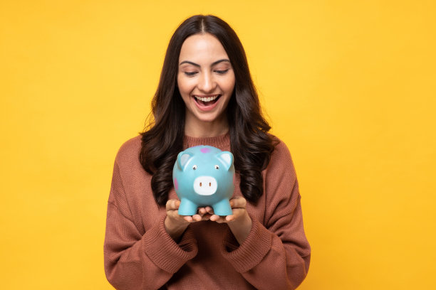 可爱的人的照片，手握钱银行猪隔离在黄色背景股票照片图片下载