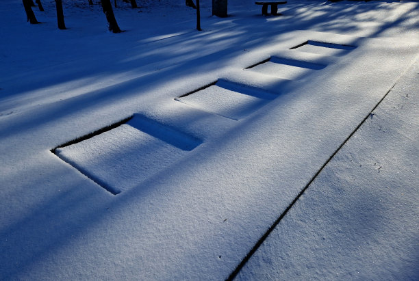 在学校操场的院子里，三个蹦床跳垫被埋在一个特殊的橡胶表面以下。周围是风景如画的后院的石墙上的木凳图片下载