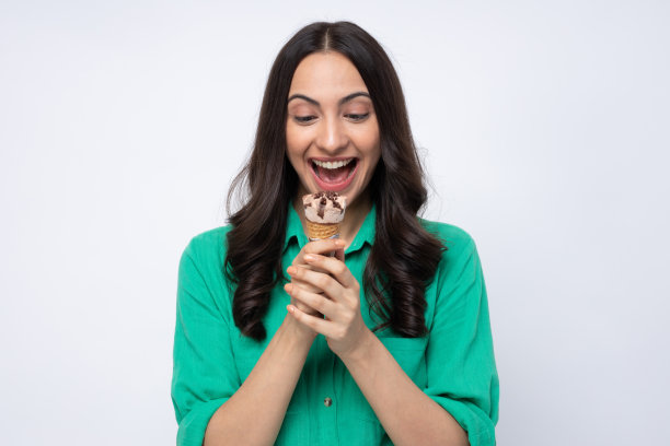 有吸引力的年轻女子吃冰淇淋，站在白色背景的股票照片图片下载