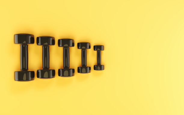 黑色塑料哑铃坐在柔软的黄色背景图片下载