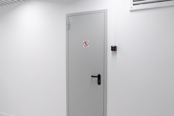 这张照片显示了一座现代建筑中一扇关闭的白色门，门把附近贴着一个清晰的禁止进入的标志，表明限制进入。图片下载