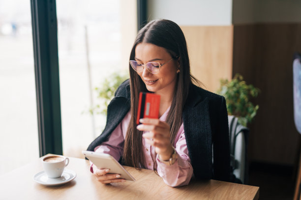 照片中，一位迷人的年轻女子在咖啡馆里使用数码平板电脑上网购物图片下载