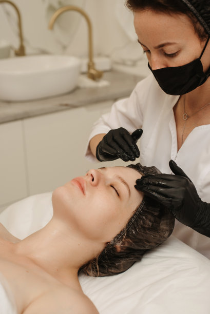 一个合格的按摩治疗师的女人的手按摩女性客户面部皮肤的俯视图。美容护理理念。垂直的照片。图片下载