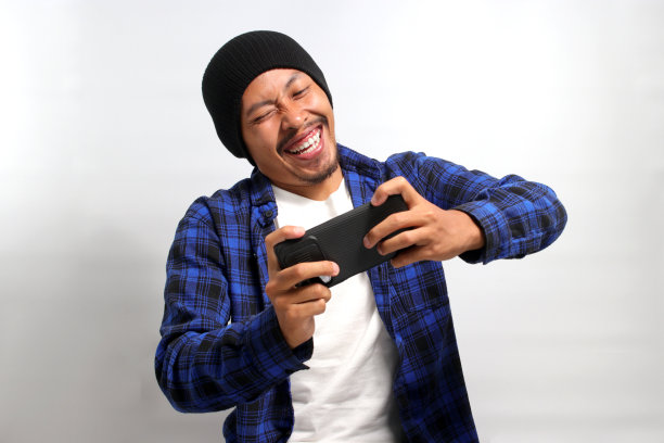 一位亚洲玩家正在用手机玩游戏图片下载