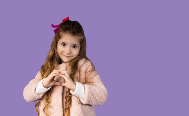 一张横幅的图片，上面有一个金发小女孩，向我们展示了她手中的一颗非常原始的心。这个女孩有着迷人的微笑和非常美丽的棕色眼睛。图片下载