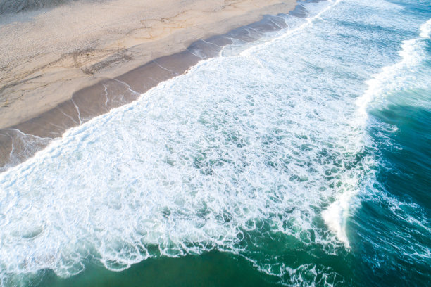 航拍的泡沫海浪冲击沙滩的照片图片下载