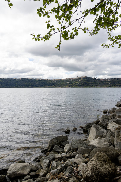 这张照片拍摄于意大利的冈多尔夫城堡，展现了湖泊和山脉的景色以及远处的城市景观图片下载
