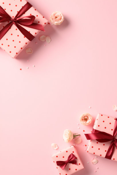 情人节礼物与红丝带蝴蝶结，玫瑰花蕾在柔和的粉红色垂直背景的俯视图照片。平的。图片下载