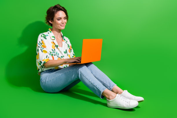 自信的年轻商务助理hr招聘女性坐在地板上使用电脑孤立的绿色背景的全长照片图片下载