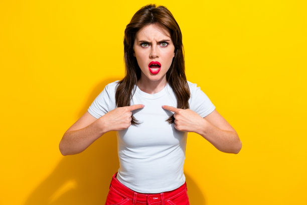 照片中，一头黑发、身穿白色t恤的愤怒、咄咄逼人的疯女人在黄色背景下对着自己图片下载