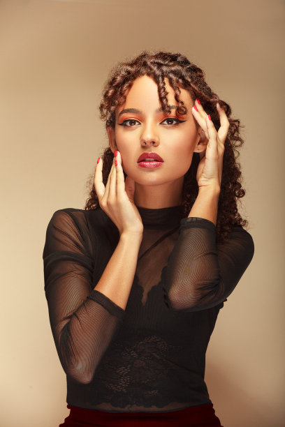 一名年轻女子的半身照片，在米色背景下，双手微妙地抚摸着她的脸图片下载