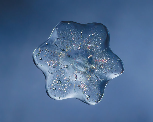 雪花在光滑的渐变背景。玻璃表面真实雪晶的微距照片。这是一朵花纹不寻常的小雪花。图片下载