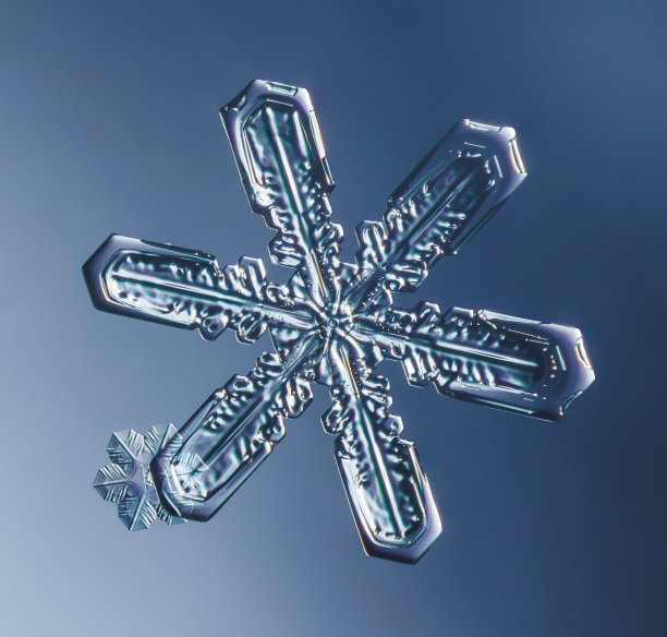 雪花在光滑的渐变背景。玻璃表面真实雪晶的微距照片。这是一朵花纹不寻常的小雪花。图片下载