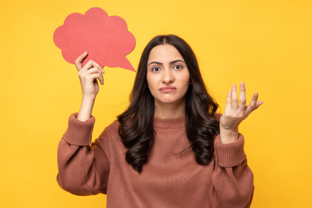 照片的年轻女子在冬天穿着抱着泡沫的思想孤立的黄色背景股票照片图片下载