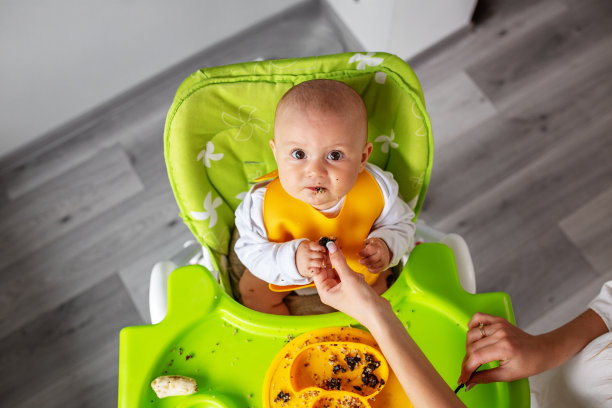 婴儿坐在高脚椅上，吃泥或粥。宝宝吃辅食。喂养的概念图片下载