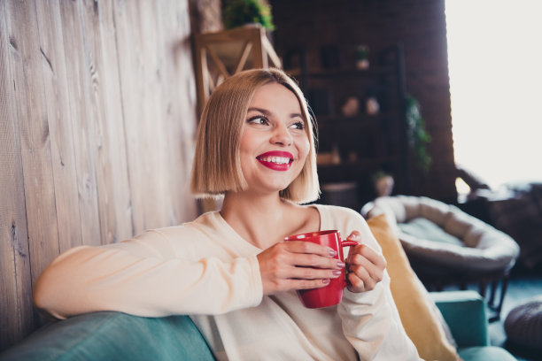 照片相当积极的女士坐在沙发上拿着新鲜的咖啡杯想象灵感消遣寒冷的公寓室内图片下载