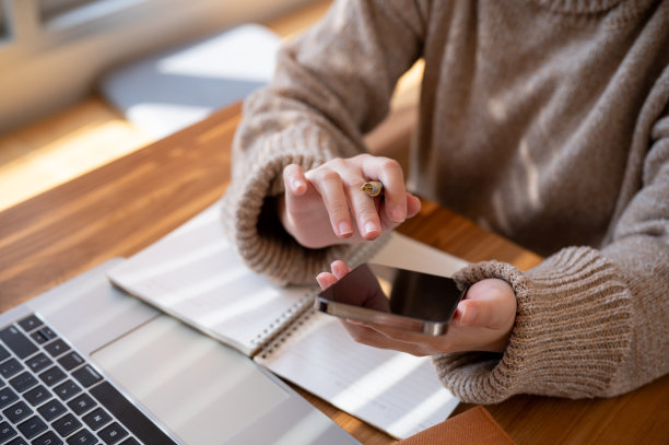 一名女子在咖啡馆联合办公空间的桌子上使用智能手机的剪辑照片。图片下载
