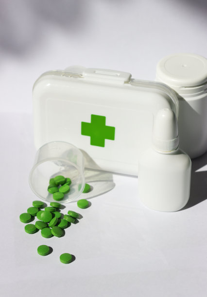 一个小急救箱，上面有药，盖子上有个十字架。附近有几瓶药。这一切都在一个白色的背景图片下载