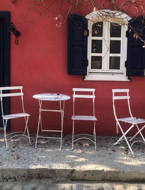 红色墙壁前的白色金属椅子。库存图片图片下载