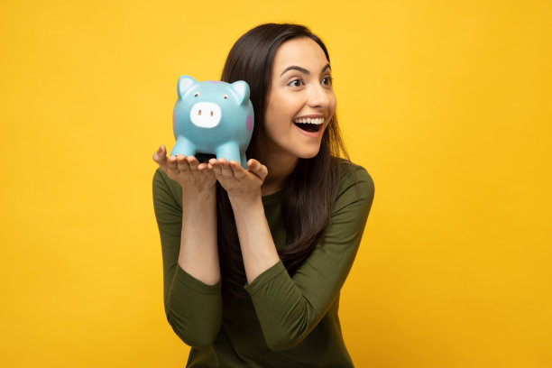 可爱的人的照片，手握钱银行猪隔离在黄色背景股票照片图片下载