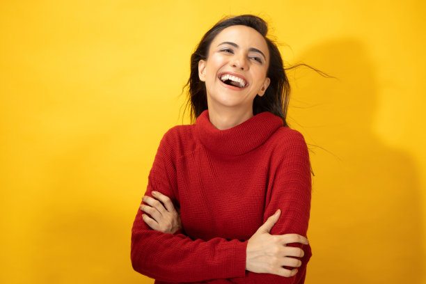 照片的年轻妇女在冬天穿站在黄色背景股票照片图片下载