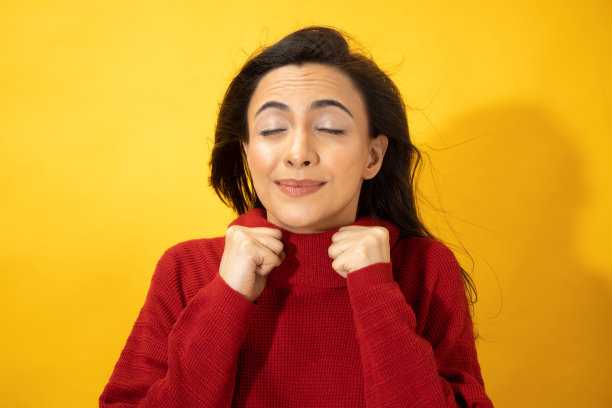 照片的年轻妇女在冬天穿站在黄色背景股票照片图片下载